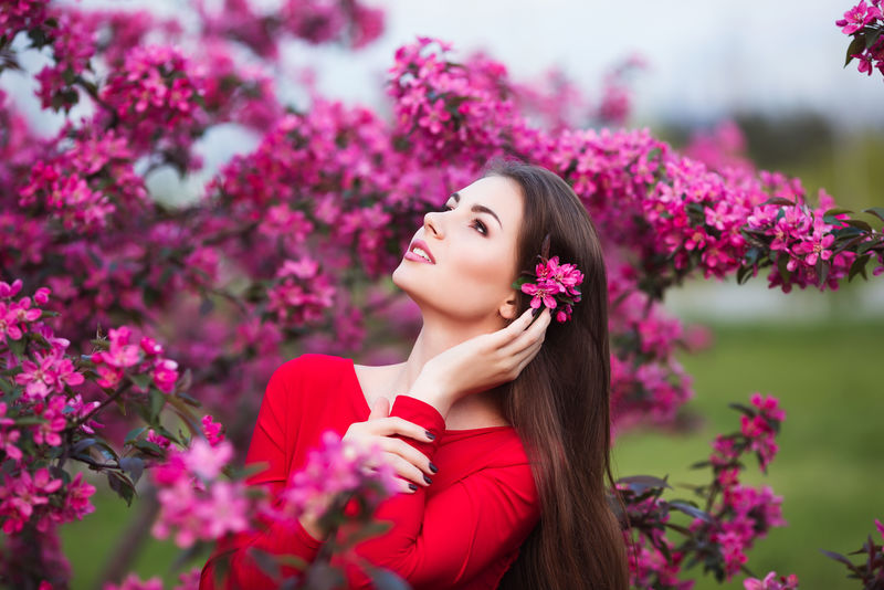 美丽的年轻女子在花木园里开满鲜花和鲜花。