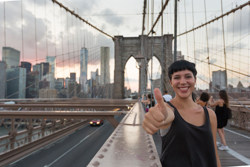 布鲁克林大桥上的快乐年轻女子竖起大拇指