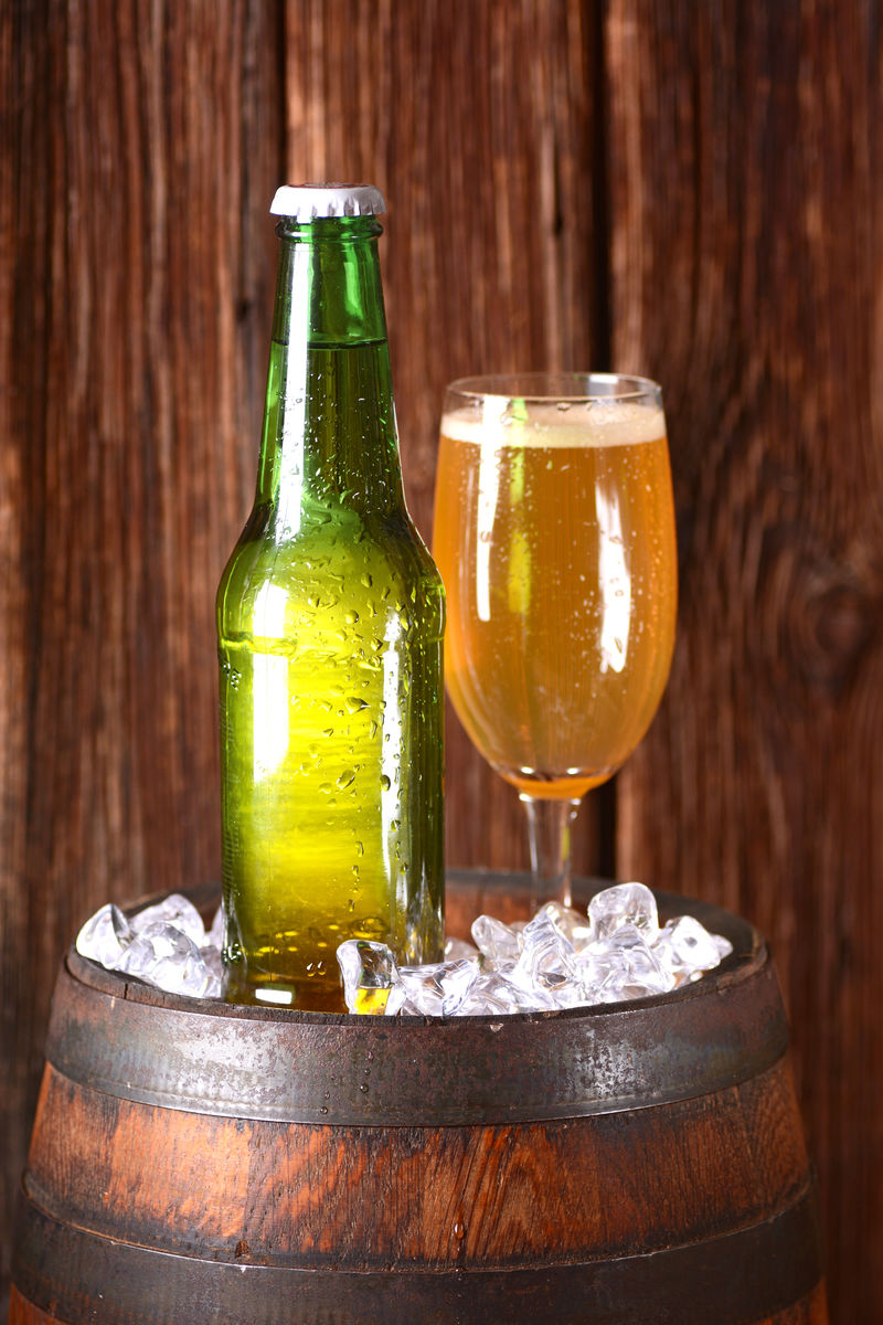 酒杯和啤酒瓶放在装有冰块的桶上