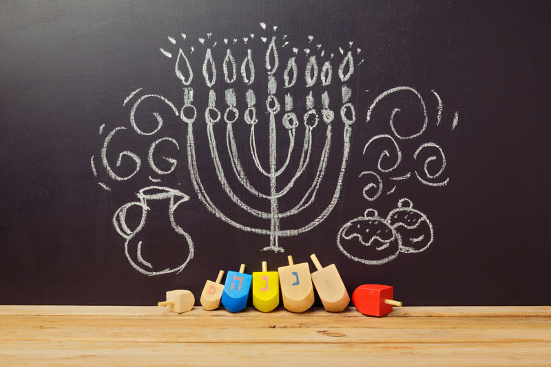 富有创意的犹太节日光明节背景，在黑板上用手绘着旋转的顶部装饰