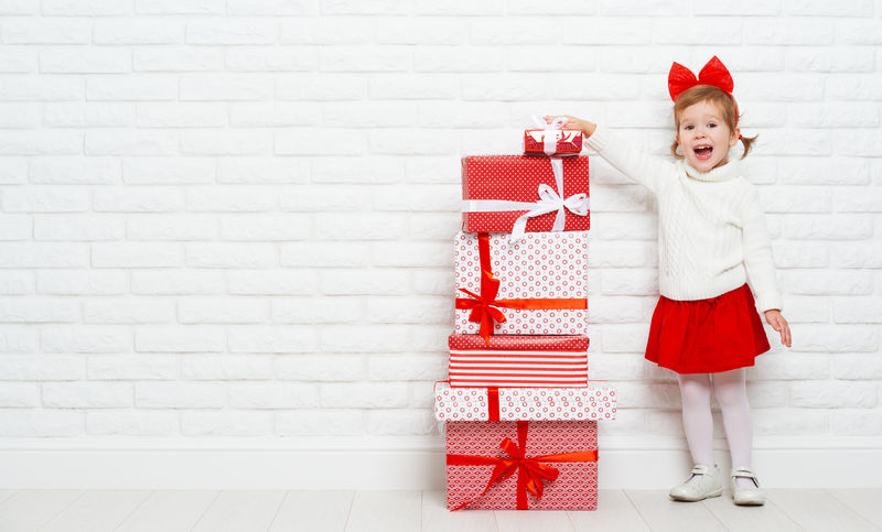 墙上挂着圣诞礼物的快乐小女孩