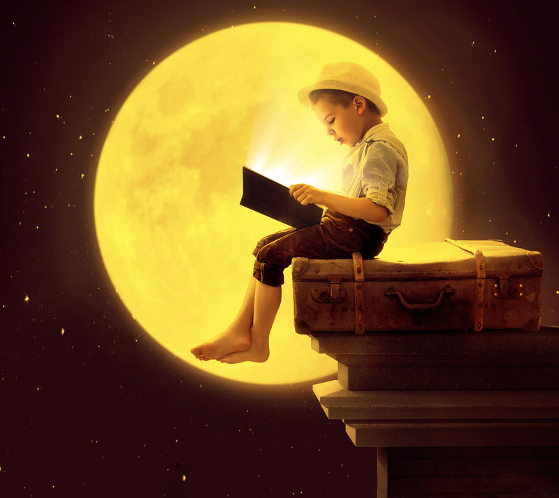 可爱的小男孩在月光下看书