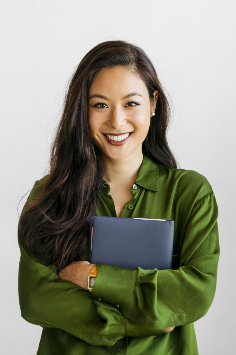 一个穿着绿色衬衫手里拿着蓝色笔记本的兴高采烈的女人