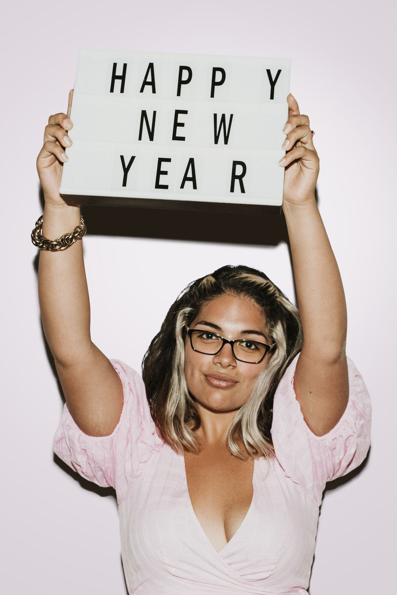 戴眼镜的女人举起快乐的新年板模型