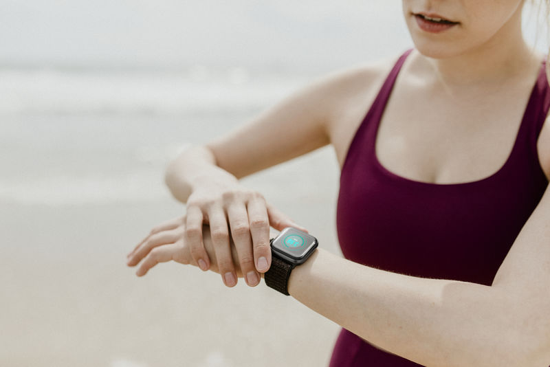 运动型女人在海滩上检查她的智能手表