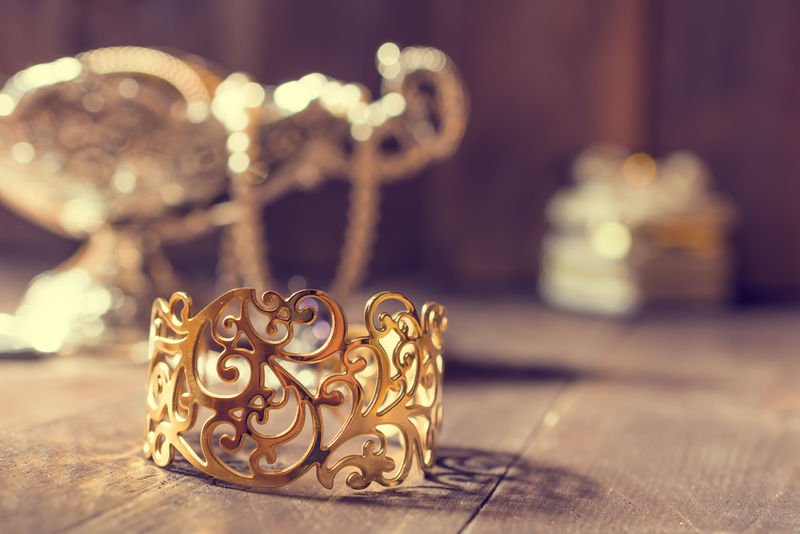 金手镯和银花瓶木质背景上有珠宝