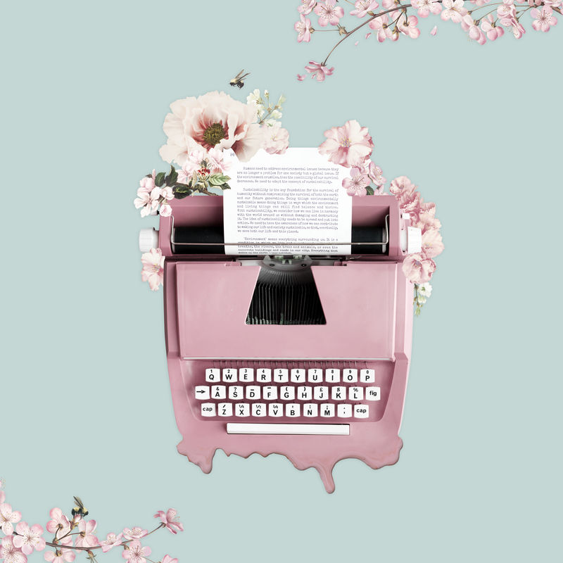 绿色背景上用花装饰的粉红色打字机
