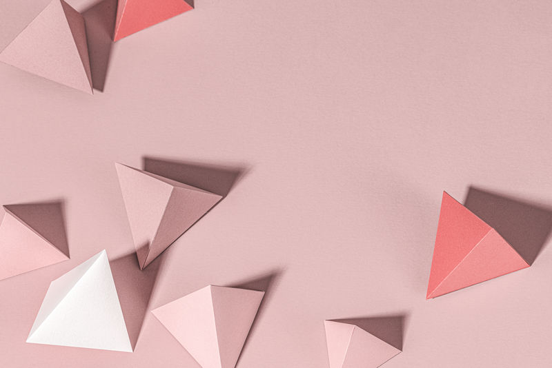 粉红色背景上的3D粉色金字塔纸工艺品