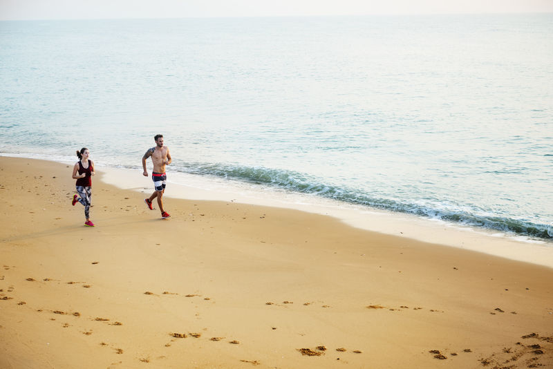 健康的年轻夫妇一起在海边跑步