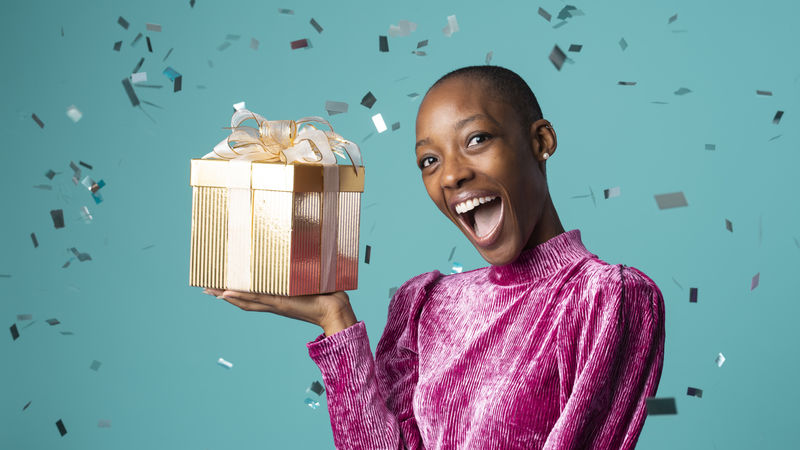 快乐的黑人妇女拿着一个绿色背景的礼品盒