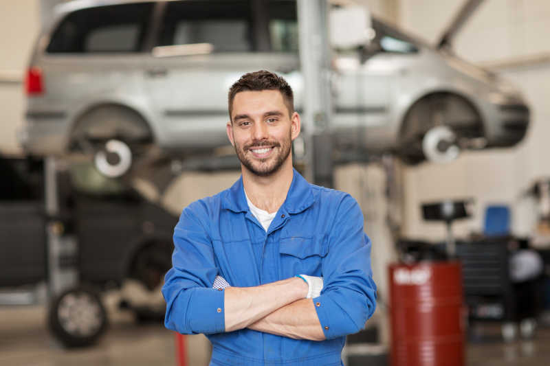 在汽车修理车间微笑的男性修理工