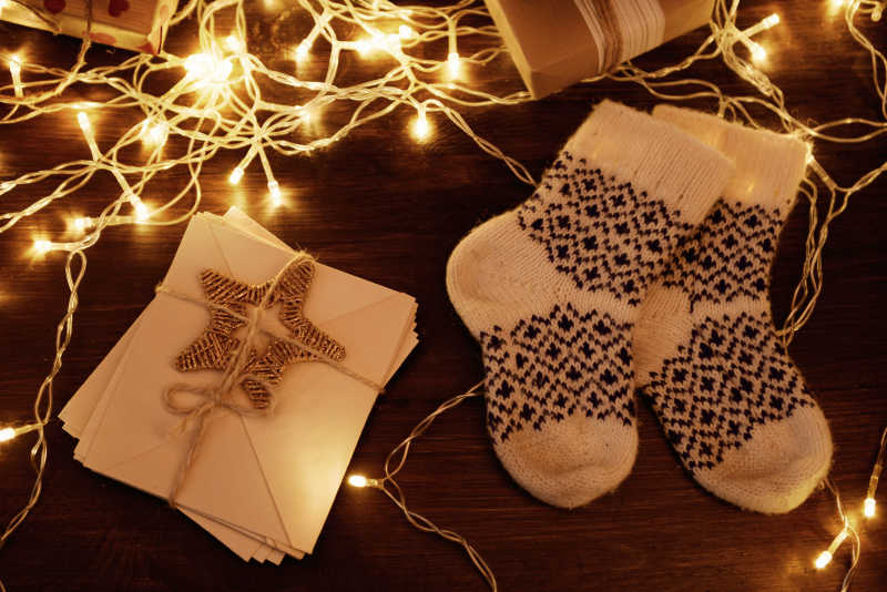 木制背景下带圣诞礼物和装饰的暖羊毛袜