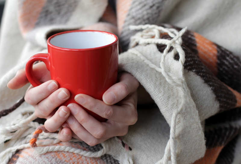 双手捂着红色咖啡杯取暖的美女