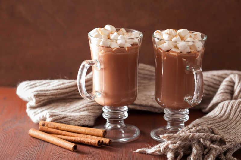 褐色背景下木桌上的一杯巧克力热饮 和一些棉花糖