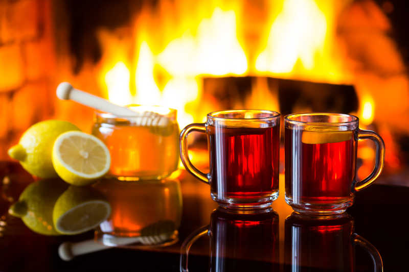 暖和的壁炉下黑色桌上的两杯热饮料