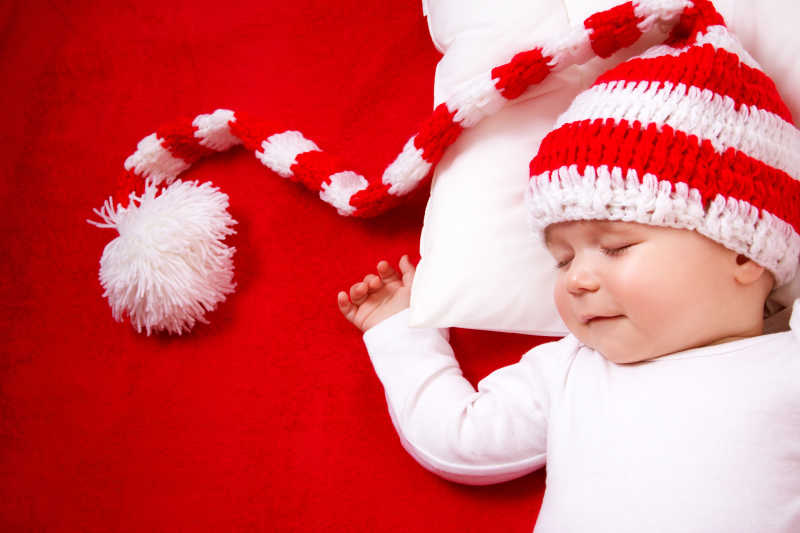 红色毯子上的戴帽子睡着的婴儿