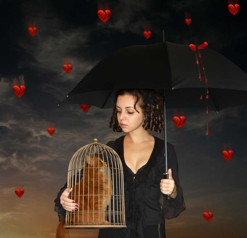 暗色天空背景下女孩打着雨伞抱着笼子里的猫