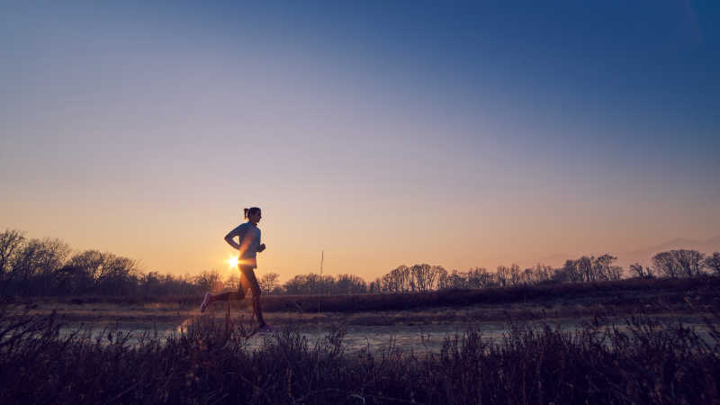 日出时乡村路上跑步的女人