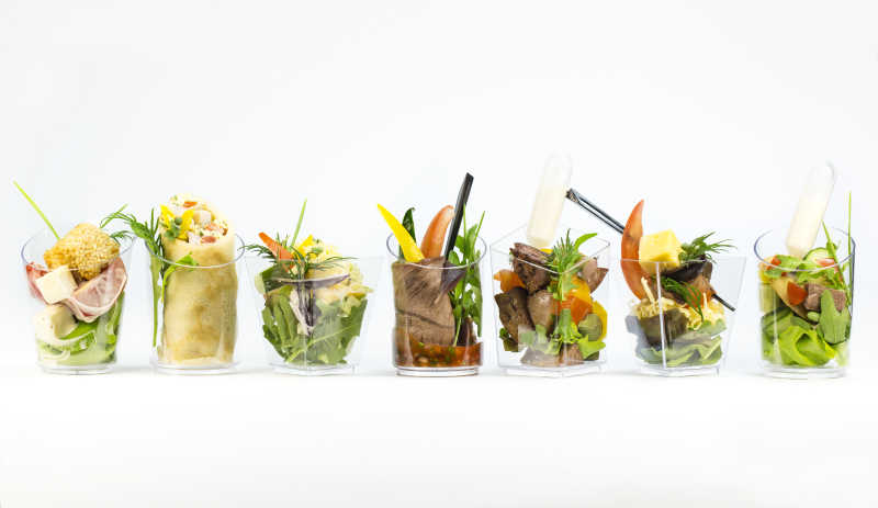 在塑料杯中的带肉和蔬菜的小型美食