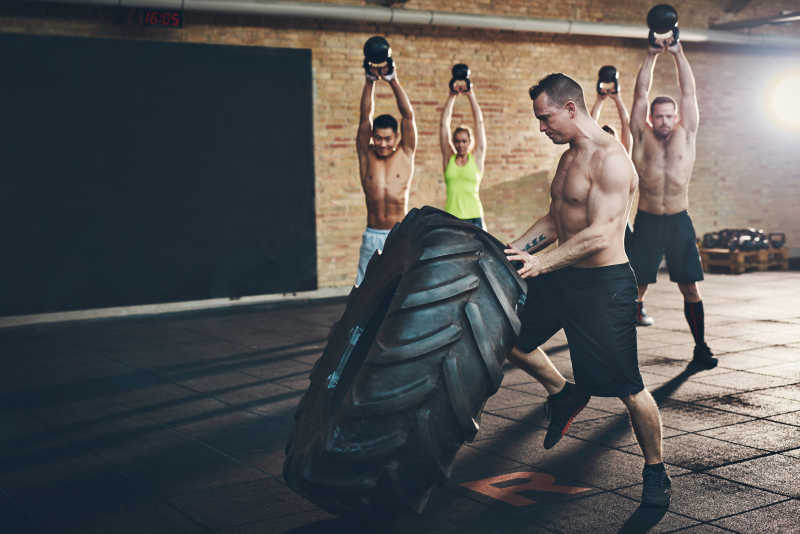 健身房里肌肉健壮的男子移动大轮胎