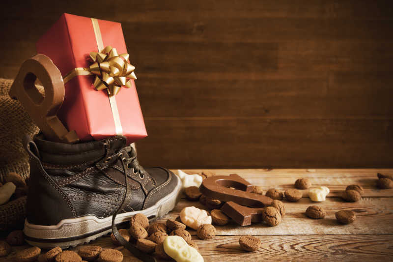 木桌上的巧克力字母糖果和放在鞋上的礼物盒