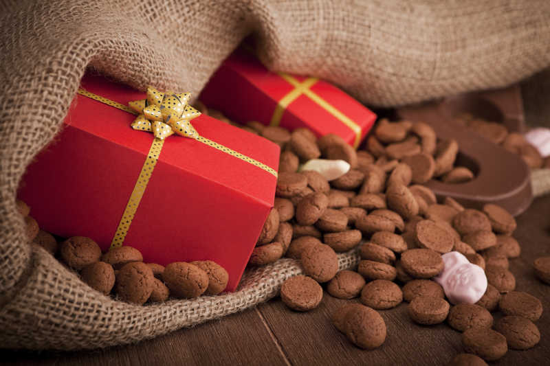 木桌上的巧克力字母糖果和红色的礼品盒