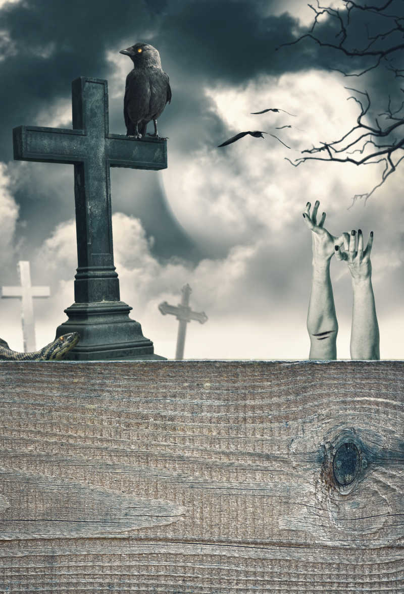 墓地的木墙上的乌鸦十字架和一双苍白的双手