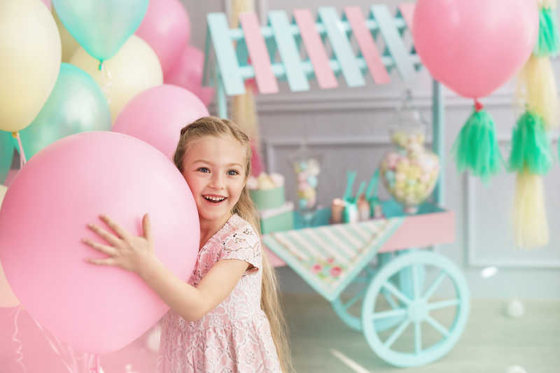 正在抱着气球微笑的小女孩