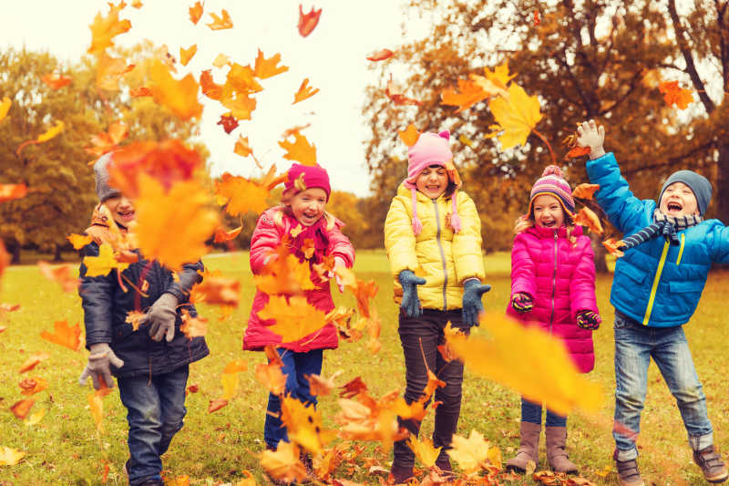 快乐的孩子们在公园里玩秋叶
