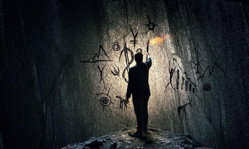 男人举着火把看黑色墙上的古老文字