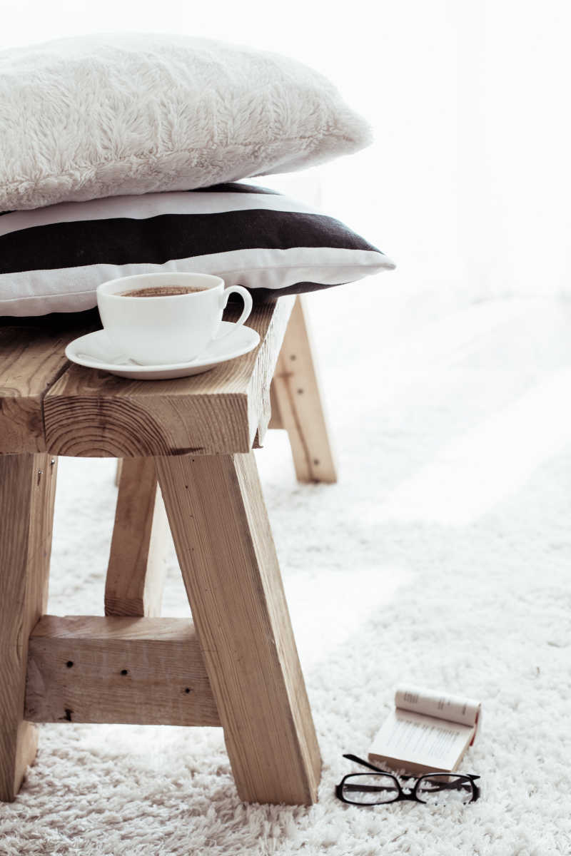 白色地毯上木凳子和黑白垫子咖啡杯