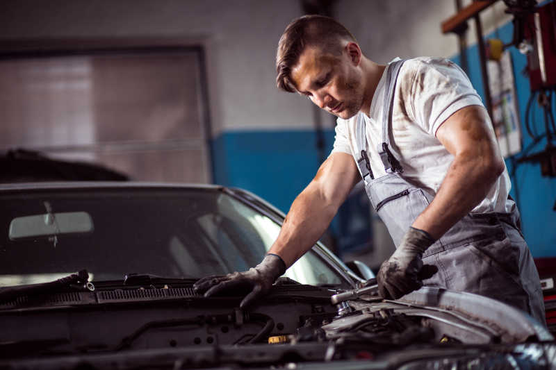汽车修理厂里正在修理汽车发动机的男性修理工