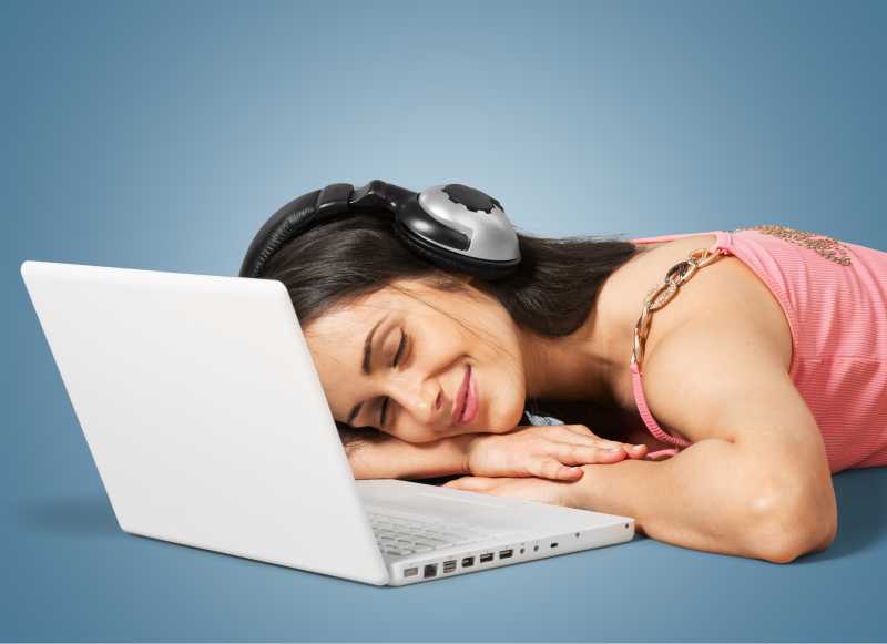 戴着耳机趴在笔记本的电脑前面的女人
