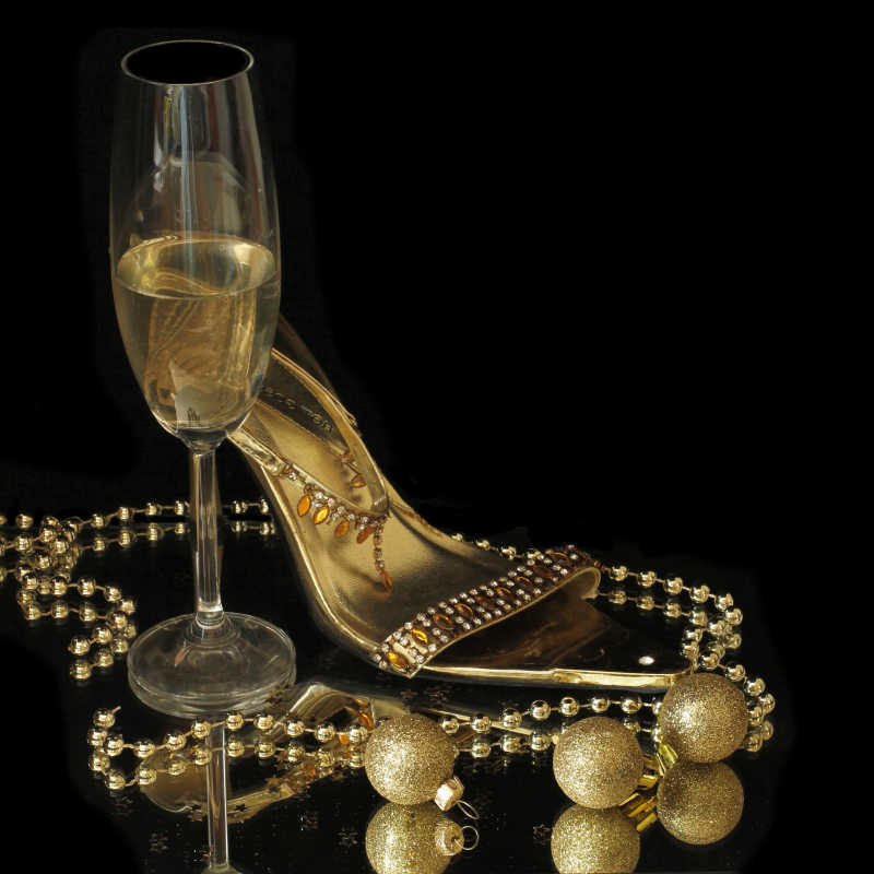 黑色背景下的香槟酒杯项链和女士凉鞋