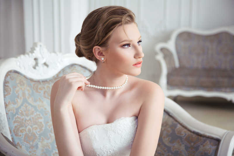 坐在卧室里戴着漂亮珍珠项链的新娘