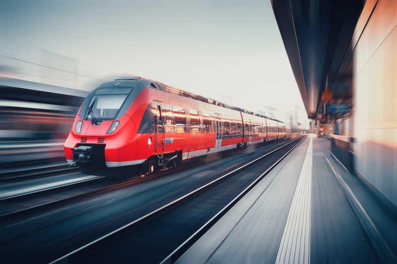 美丽的火车站与现代高速红色通勤列车与运动模糊效果日落在纽伦堡