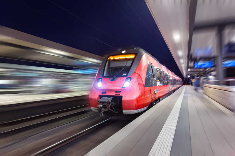 现代高速红色旅客列车夜间通过火车站