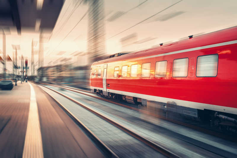 现代高速红色乘客通勤列车在日落时在铁路站台上运行