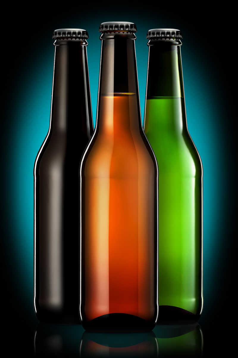 黑色背景下的三种不同颜色玻璃酒瓶