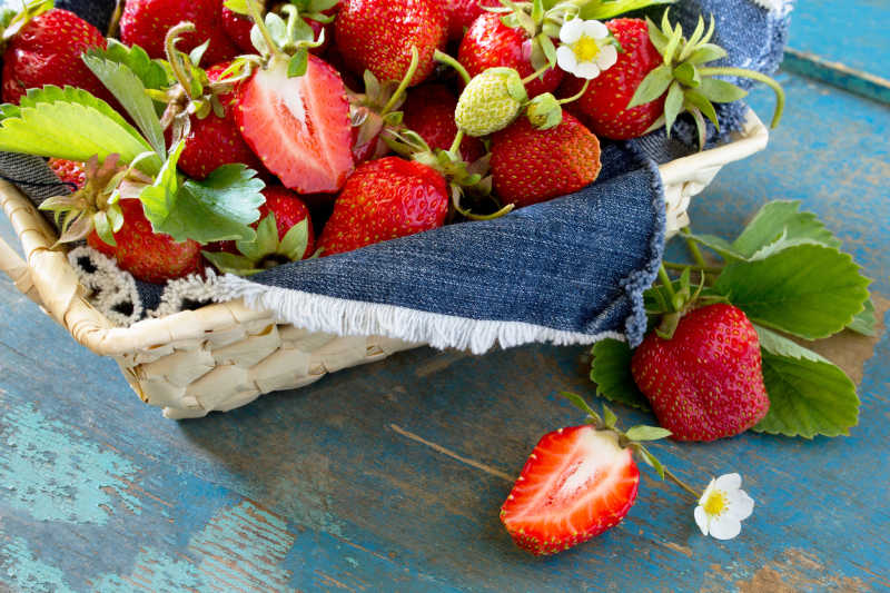 木桌上新鲜的成熟草莓在柳条筐上