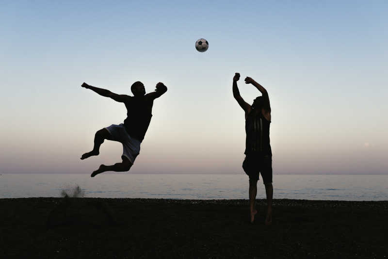 沙滩上踢足球的两个男人剪影
