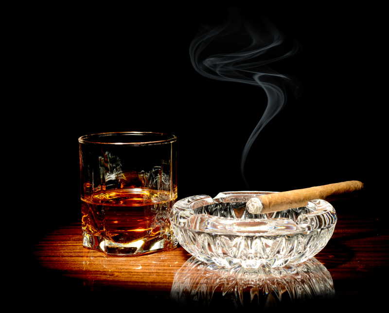 聚光灯下的威士忌和烟灰缸中的雪茄