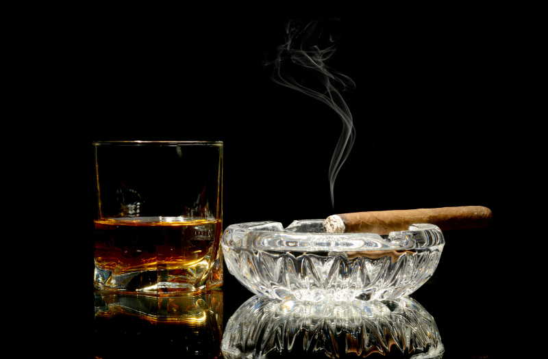 黑背景中的桌上的威士忌和雪茄雪