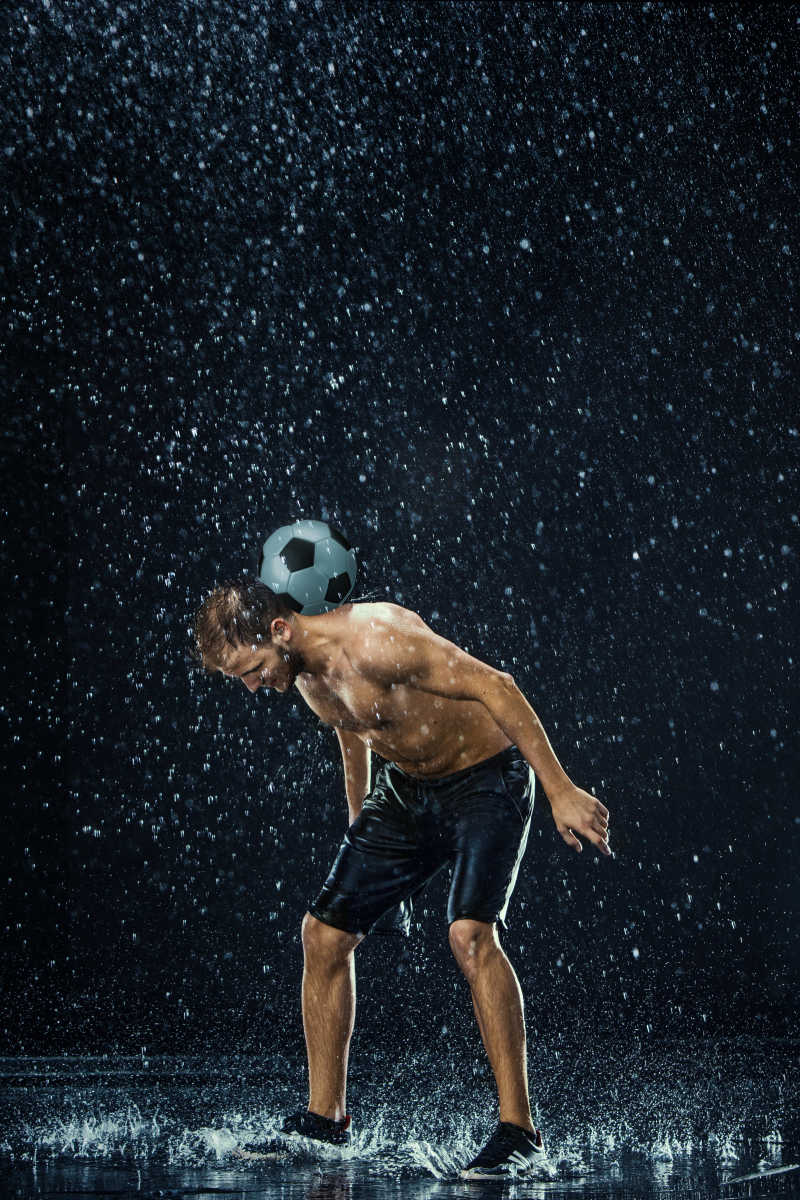 黑色背景下正在玩足球的运动员周围的水滴