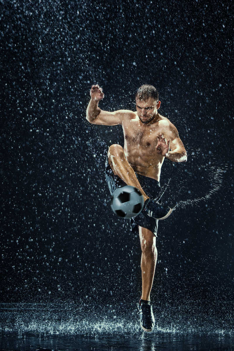 水在黑背景的足球运动员附近滴下