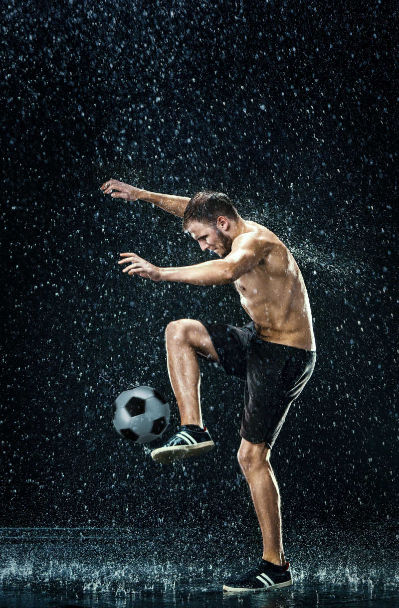 水在黑色背景下足球运动员周围滴下