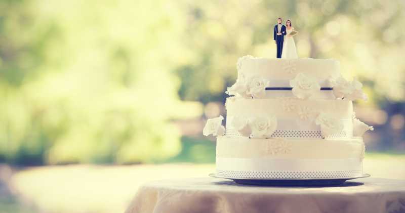 白色的婚礼蛋糕上有新郎新娘的玩偶装饰