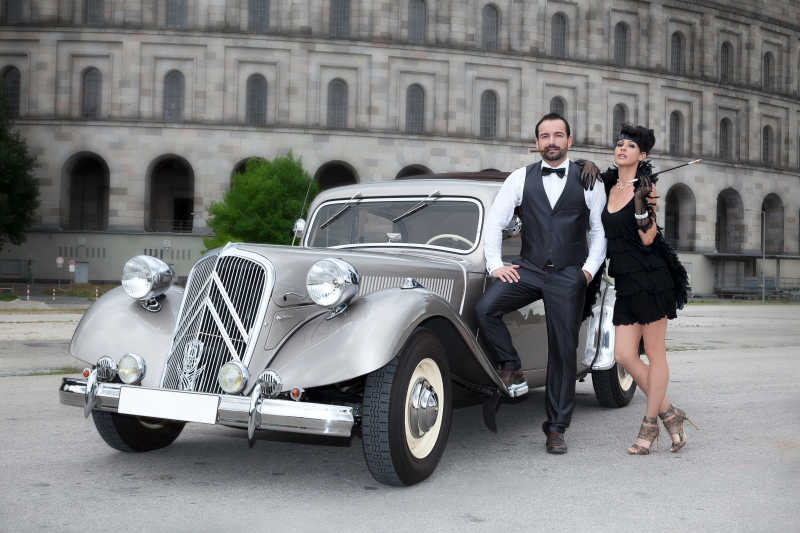 镜头下时尚的银色老式汽车边的一对年轻情侣模特