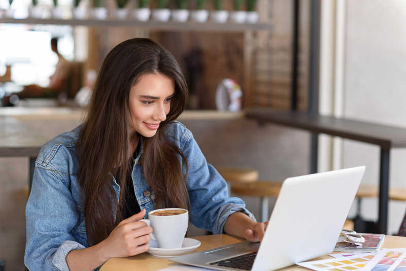在咖啡馆里玩电脑喝咖啡的女人