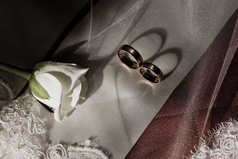 丝绸上的订婚戒指和白玫瑰